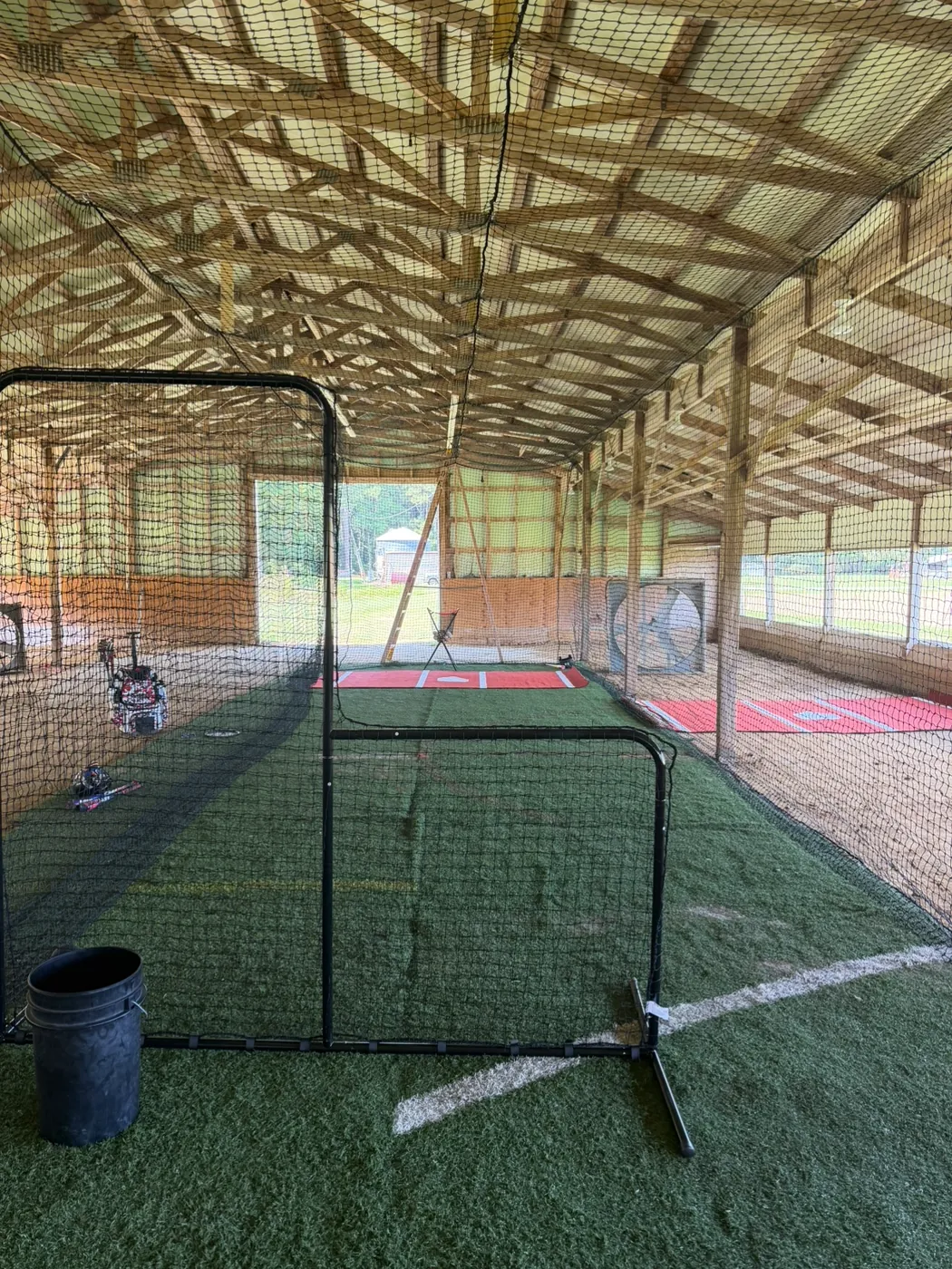 Netted batting cage with an L-screen on turf